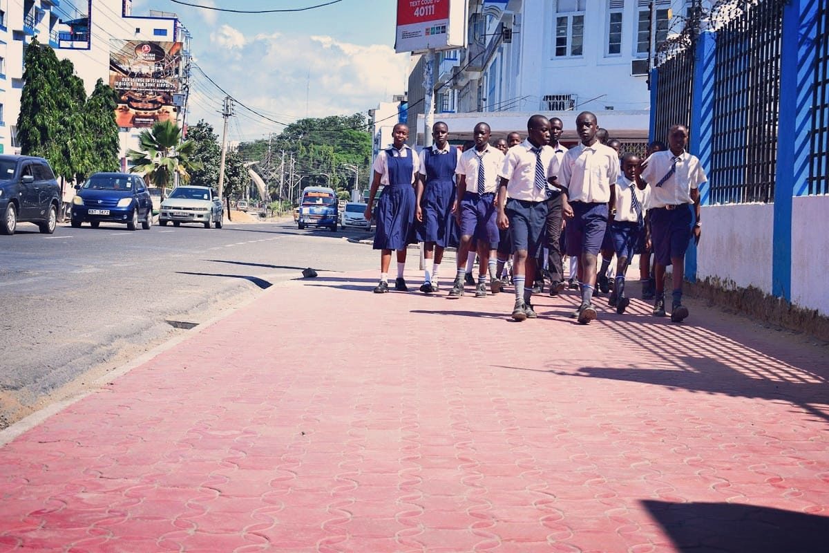 School children walk on sidewalk in Mombasa