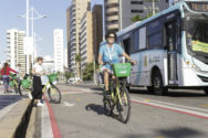 Ana Nassar of ITDP Brazil on bike from Fortaleza bikeshare, Bicicletar, with Fortaleza bus in the background