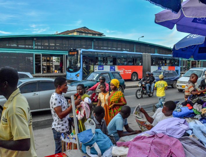 People standing in front of a blue DART bus in Dar es Salaam, Tanzania.