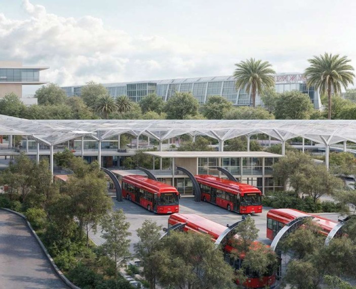 Red buses parked at a modern transit hub with glass canopies and palm trees on a sunny day.