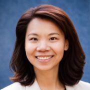Smiling Asian woman with shoulder-length dark hair against a blue background (portrait).