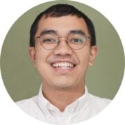 Smiling young man with round glasses in a circular portrait on a green background, wearing a white shirt.